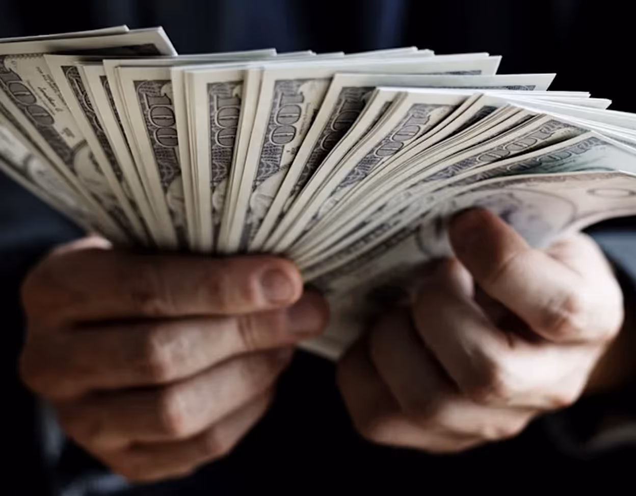Person holding money representing rags-to-riches financial growth.