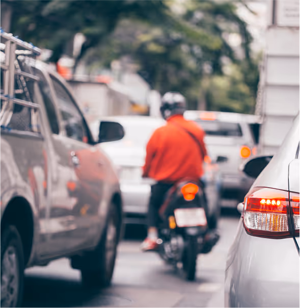 Motorcyclist lane-splitting between vehicles in Texas traffic.
