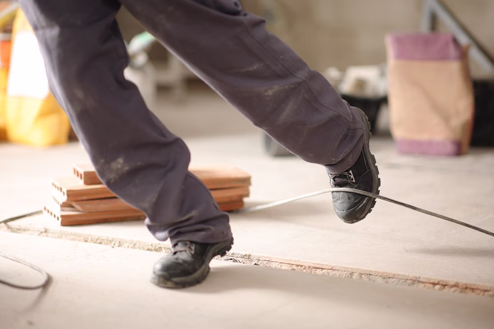 Worker tripping over loose wires at a construction site during a construction accident.